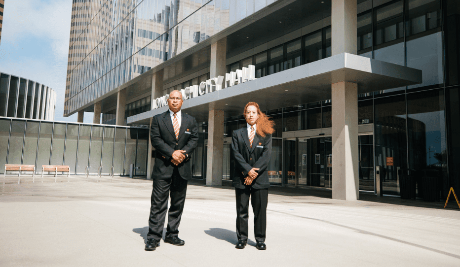 Two professional security personnel in formal uniforms providing security services outside a modern building