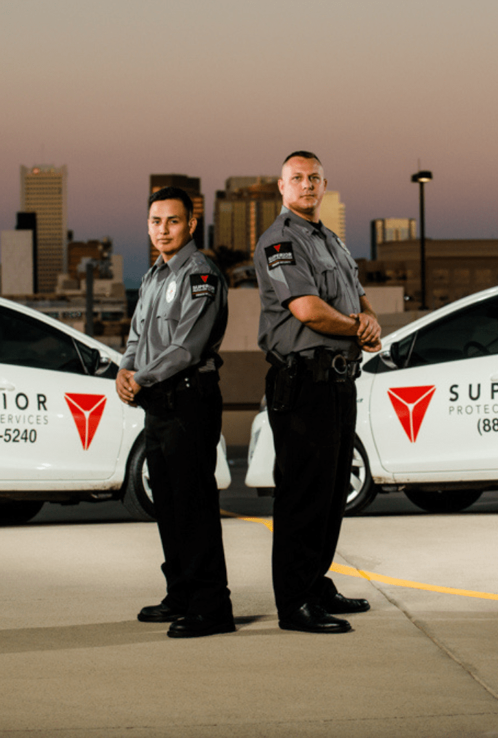 Two Superior Protection Services guards standing in front of two patrol cars, ready to provide mobile patrol services to ensure the safety and security of the community.