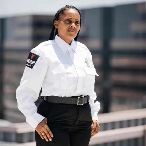 A confident female security officer in a white uniform providing professional security services in an urban setting