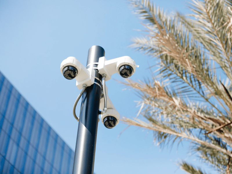 A high-tech security services surveillance camera mounted on a pole, monitoring an urban area