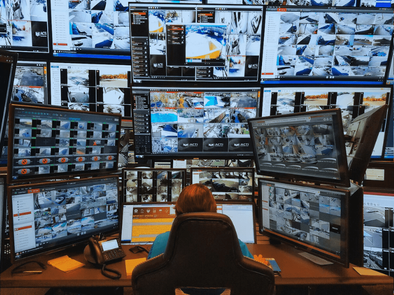 A Superior Protection Services guard attentively monitoring multiple screens displaying live video feeds as part of their live video monitoring service.