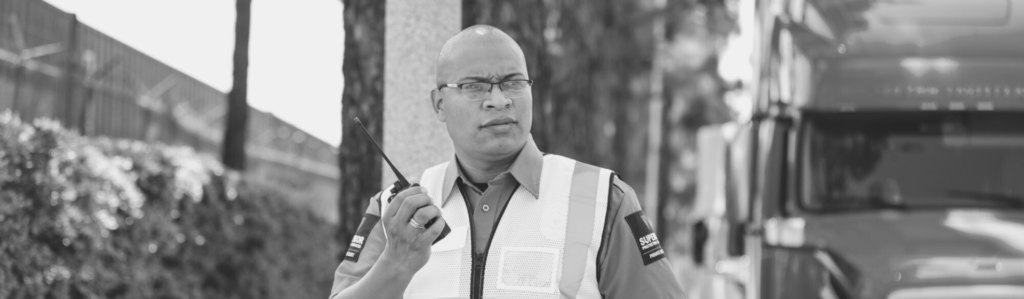 A male Superior Protection Services guard holding a walkie-talkie, ready to respond to any security needs and representing the company’s commitment to providing reliable protection services.